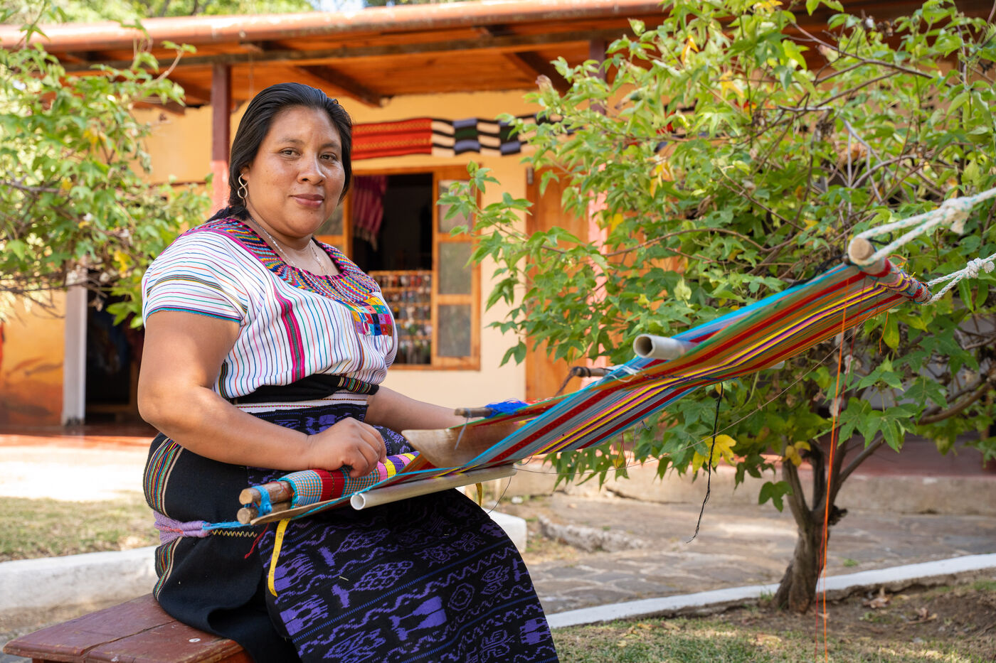 Artesana tejiendo en telar de cintura en el jardín